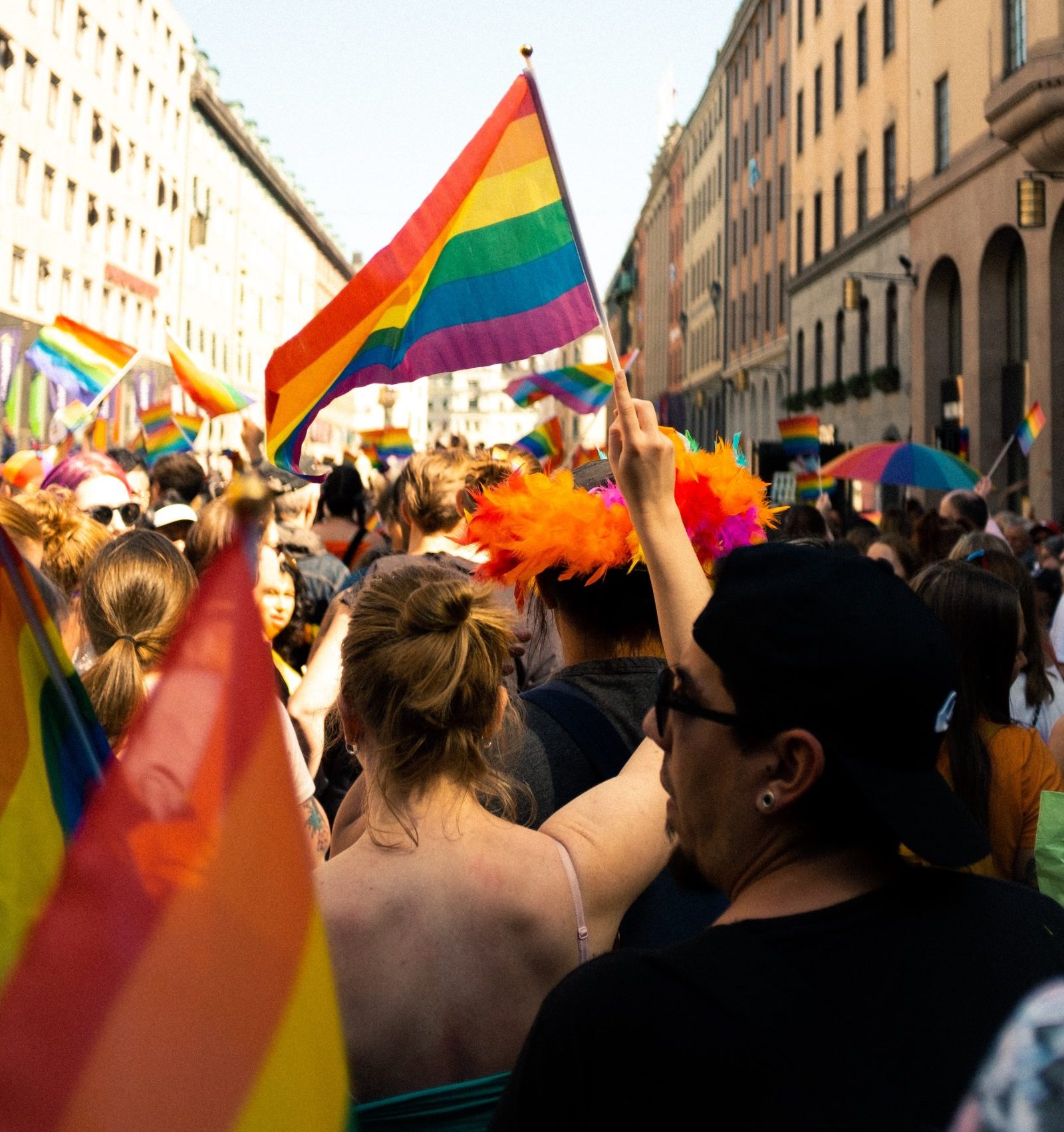 Eine Gruppe von Menschen feiert queere Akzeptanz und demokratische Vielfalt, indem sie während CSDs Regenbogenfahnen hochhält.