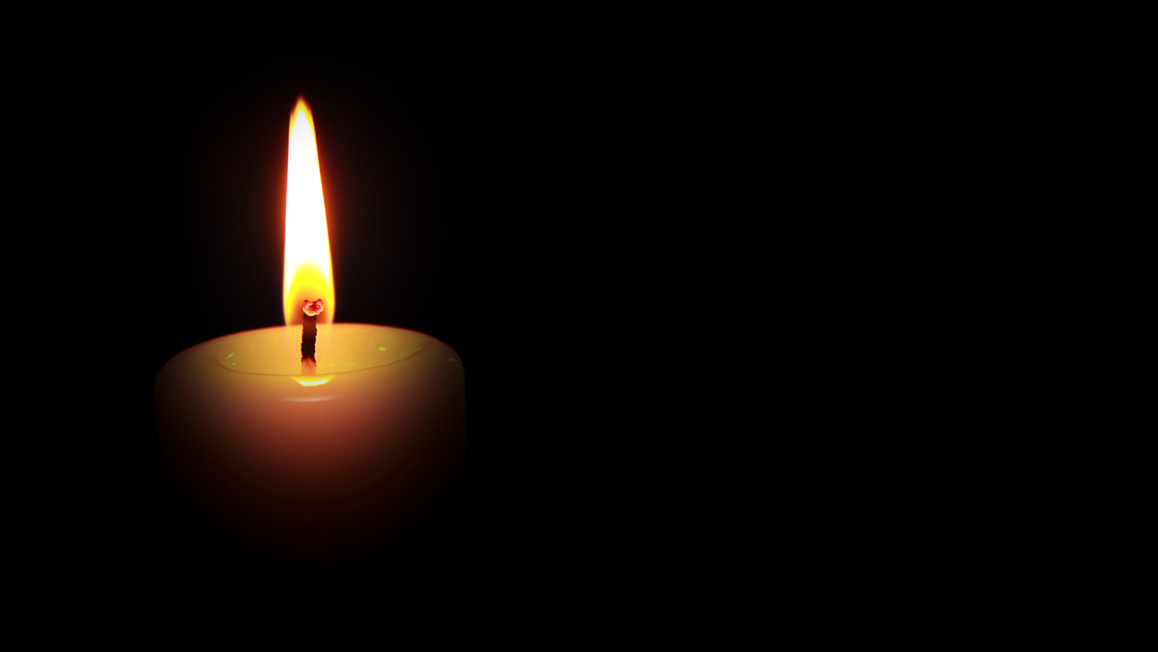 Auf schwarzem Hintergrund wird eine Kerze angezündet, um Brigitte Maser, einer verstorbenen Aktivistin, zu ehren.